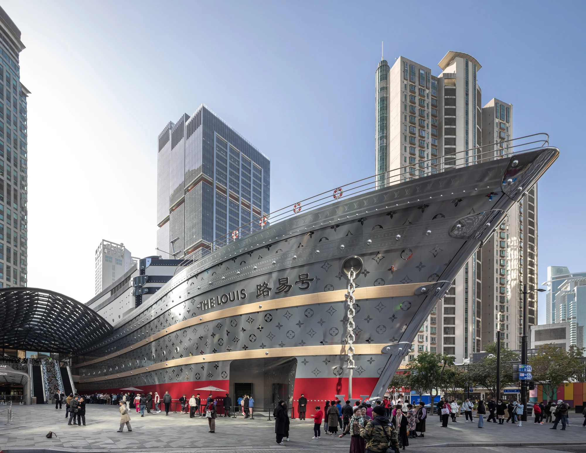 The Louis ship-shaped Louis Vuitton building in Shanghai, with a metallic monogrammed bow and pedestrians in front.