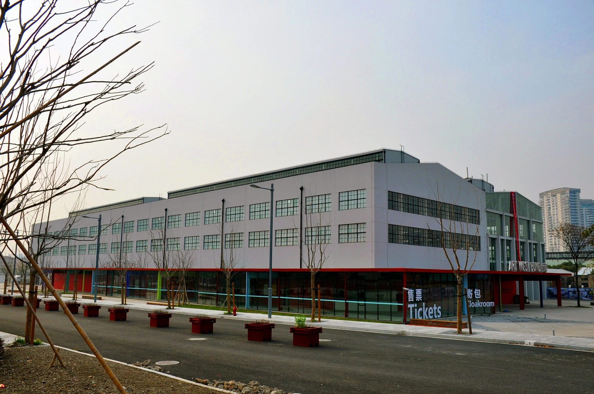 West Bund Art Center’s long white former industrial building, with ticket and cloakroom signs in an archival exterior photograph.