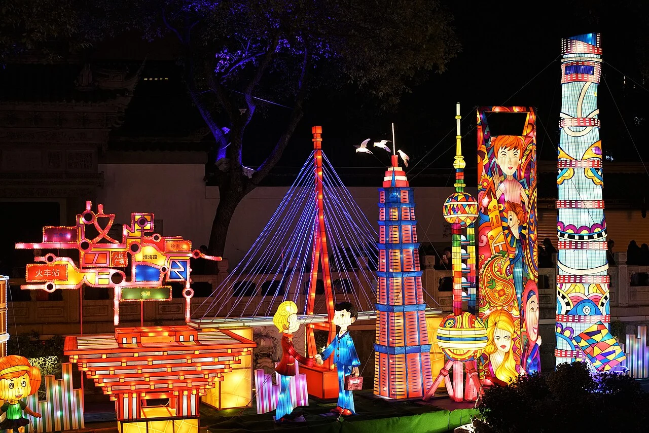 Illuminated towers, a bridge and character figures in a Yuyuan lantern display.