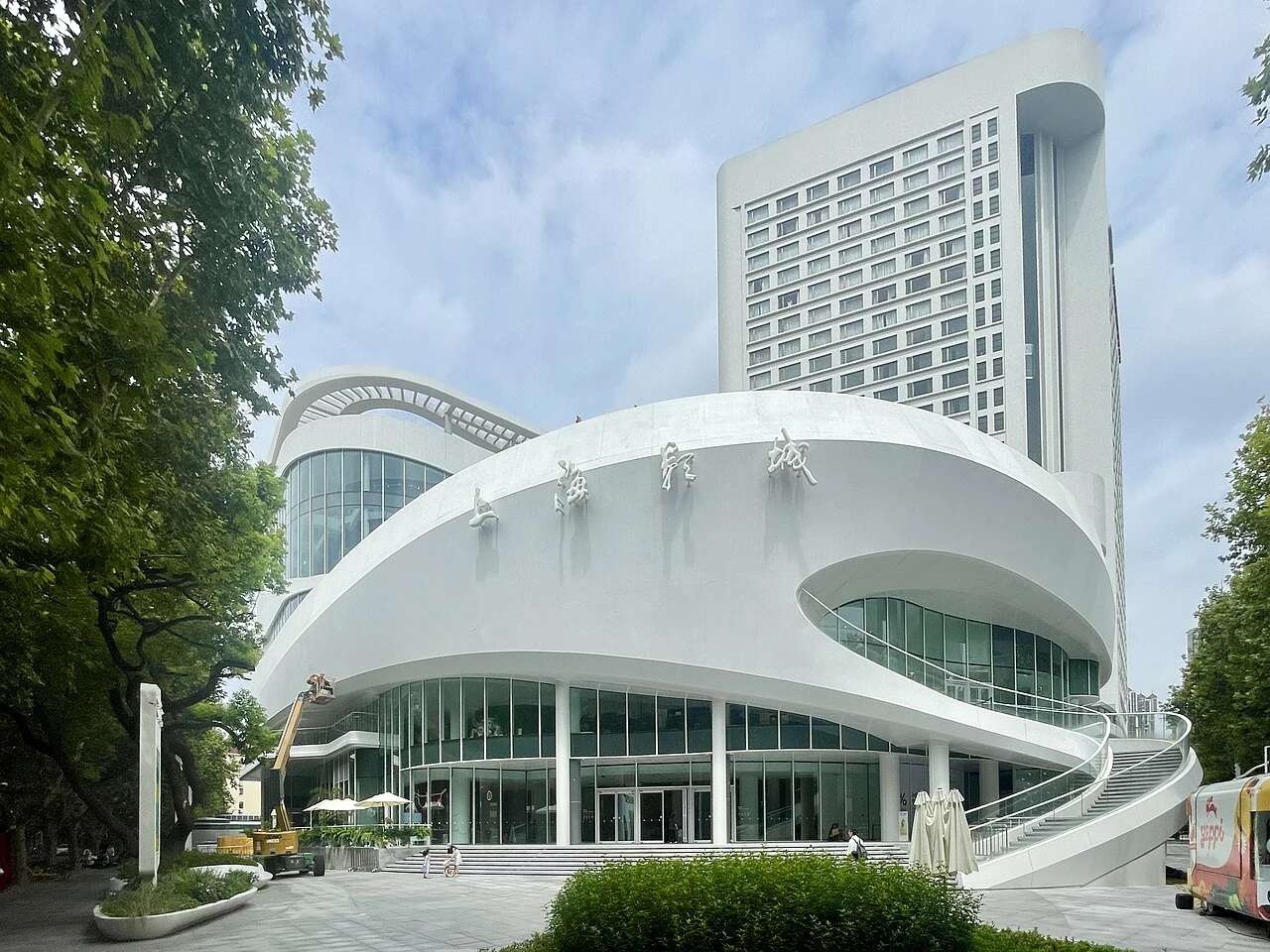 Shanghai Film Art Centre’s curving white facade and Chinese cinema sign beneath a taller hotel building.