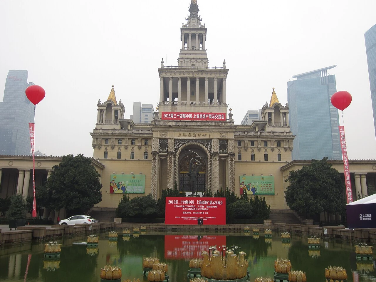Shanghai Exhibition Centre’s spire and symmetrical wings reflected in its forecourt pool.