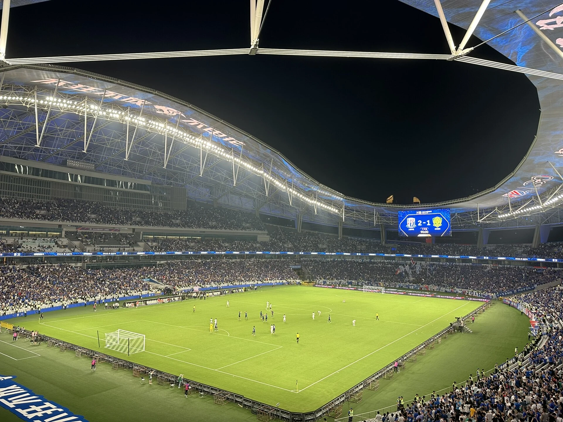 Shanghai Stadium with a football match and a full crowd under floodlights