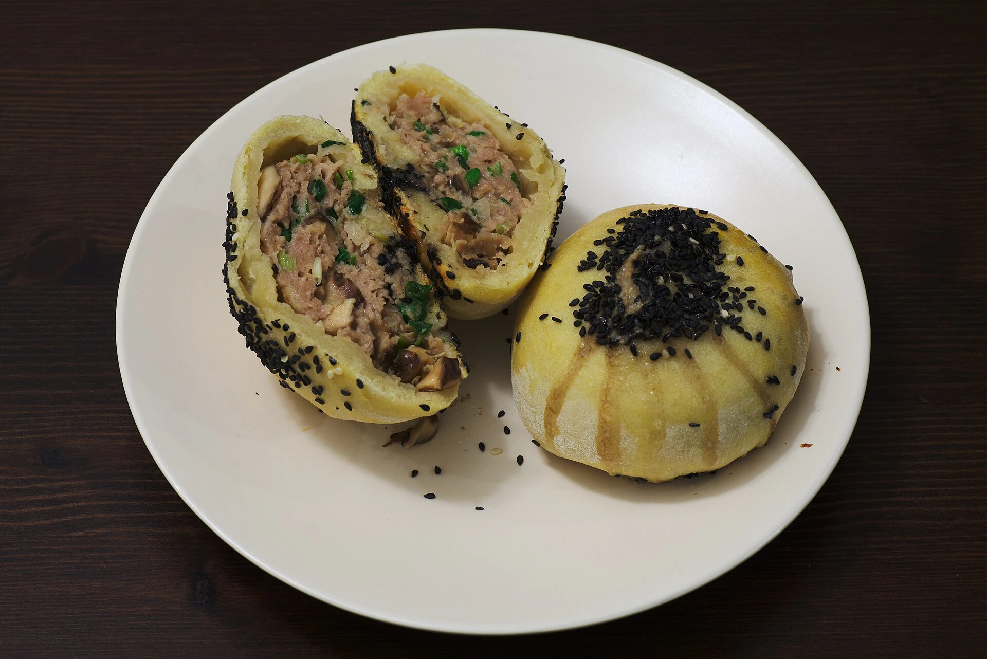 Homemade savoury Suzhou-style meat mooncakes, one cut open to show the filling